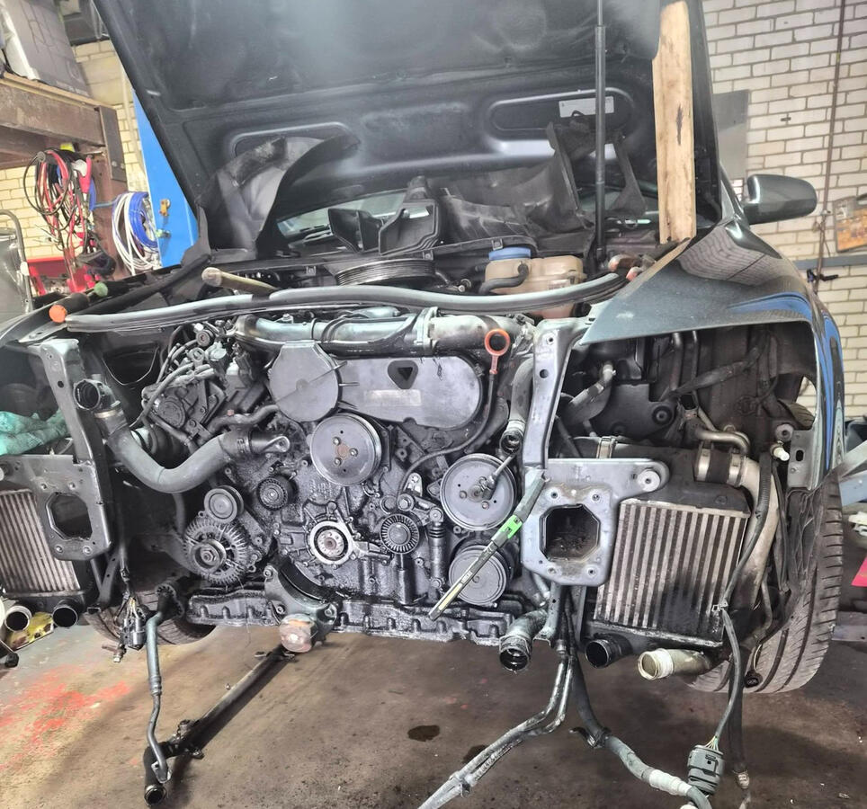 Audi with bumper, headlights and slam panel removed showing front of engine